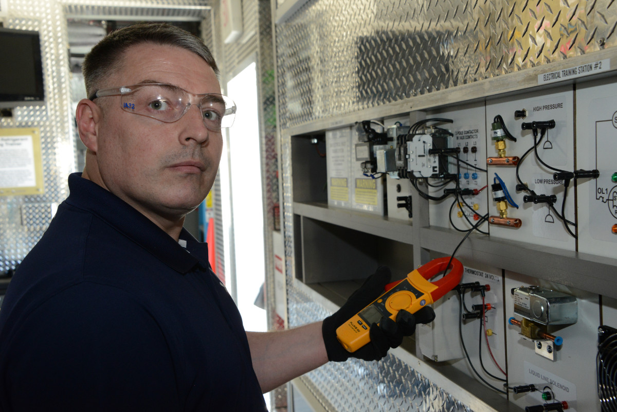 HVAC training instructor holding fluke inductive multi-meter at the electrical training station